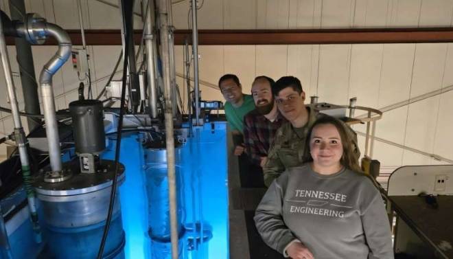 从后往前：布兰登&middot;威尔逊、布莱恩&middot;康瑞、帕维尔&middot;希伦科和艾米丽&middot;哈金斯聚集在俄亥俄州立大学研究反应堆周围，准备使用INSET炉对涂层替代粒子进行辐照测试