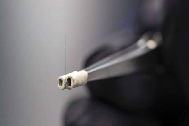 碳纤维被准备安装在一个装置中,以测试其与聚合物基质的附着力。ORNL的研究人员正在使用聚合物纳米纤维来提高碳纤维复合材料的附着力,从而提升其性能