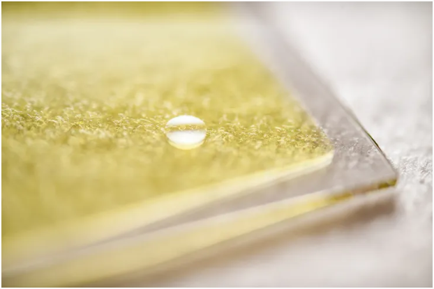 用于生产氢燃料的三层太阳能材料的特写,其中一滴水突出了其反应表面。 图片来源:林雪平大学/Olov Planthaber