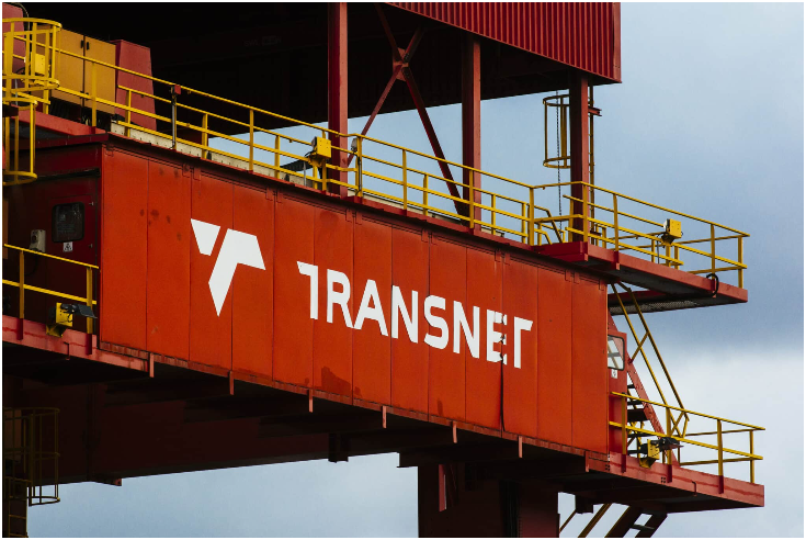 2018年5月25日，星期五，南非德班，Transnet的标识矗立在由特雷克斯公司制造的轨道式龙门起重机上。该起重机位于德班港，由Transnet SOC控股有限公司旗下港务局运营。由于货运需求低于预期，Transnet去年将其七年资本投资计划削减了17%，至2292亿兰特。摄影：Waldo Swiegers/Bloomberg via Getty Images