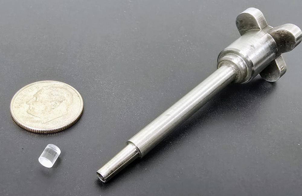 W7-X 系统成型的颗粒塑料复制品，旁边是一枚一角硬币，用于尺寸参考，以及从挤压件中取出颗粒的切割器，如下方视频所示。图片：Larry Baylor/ORNL，美国能源部