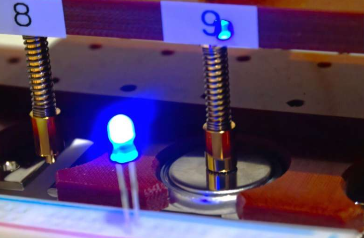 纽扣镁电池原型,采用新开发的非晶态氧化物阴极,为蓝色发光二极管 (LED) 供电。由于点亮 LED 需要超过 2.5 伏的电压,这表明该电池能够产生足够的电压,并向外部电路供电。