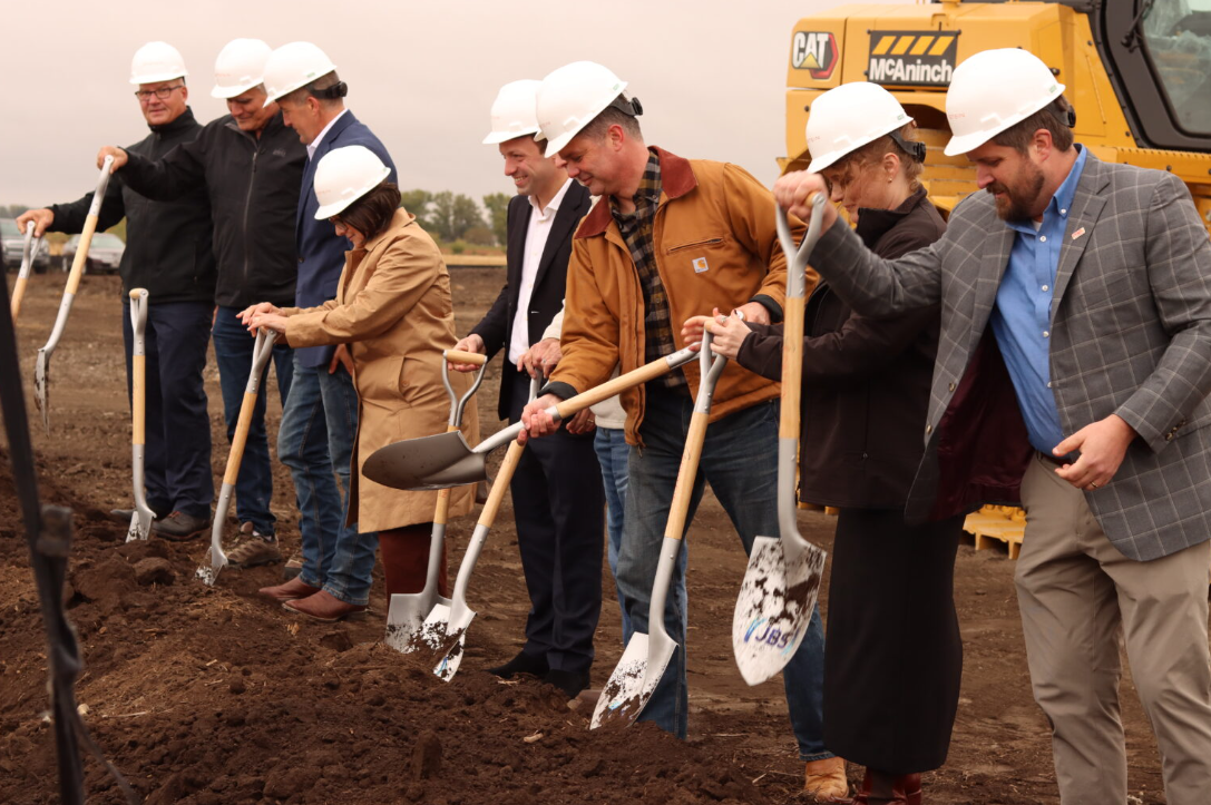 爱荷华州佩里市，官员们为一家新的香肠生产厂破土动工。从左至右：JBS预制食品公司总裁里克·福斯特；佩里市市长德克·卡瓦诺；爱荷华州农业部长迈克·奈格；经济发展局局长黛比·达勒姆；JBS美国公司首席执行官韦斯利·巴蒂斯塔-菲略；JBS佩里公司总经理迈克·蔡斯；美国众议员扎克·纳恩；大达拉斯县发展联盟的雷切尔·瓦克尔；以及佩里市行政长官斯文·彼得森。
