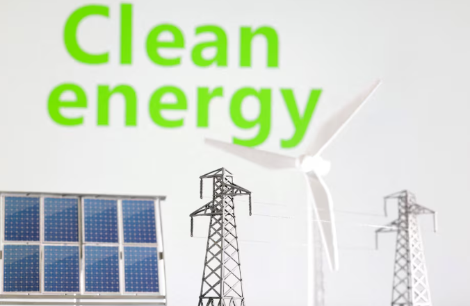 这张于 2023 年 1 月 17 日拍摄的插图中,“清洁能源”字样前有风车、太阳能电池板和电线杆的微缩模型。