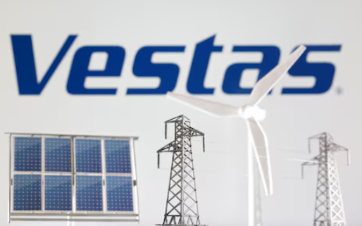 这张拍摄于 2023 年 1 月 17 日的插图中,维斯塔斯标志前有风车、太阳能电池板和电线杆的微缩模型。