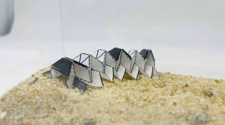 用Miura-Ori折纸图案制作的爬行机器人。深色区域覆盖一层磁性橡胶薄膜,使机器人能够移动。